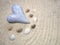 Stone heart on gray sand and shells - selective focus