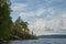 stone island overgrown with trees in the middle of the water. blue sky with clouds. northern landscape