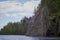 stone island overgrown with trees in the middle of the water. blue sky with clouds. northern landscape