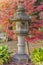 Stone Kasuga lantern under a red maple momiji in the garden of Rikugien in Tokyo in autumn