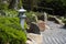 Stone lantern between evergreen plants, rocks and raked gravel,