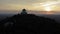 A stone medieval tower on top of a mountain at sunset