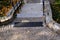 Stone park long staircase with short platforms. of paved granite paving blocks. short black metal railing interrupted several time
