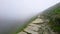 Stone pathway disappearing to vanishing point with drop over edge into fog high up at narrow point on PYG trail on Mount Snowdon i