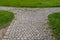 Stone paved road divided in two directions among green grass