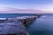 Stone pier in a tranquil blue sea under dusk sky