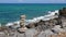 Stone pyramid on Crete rocky seashore against blue sea