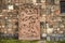 Stone red plate with carved stylized figures of people,domestic and wild animals and snakes at the wall of a fortress in city Asht