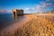 Stone and rocks beach with nobody close to a bunker and a scenic blue sky with clouds