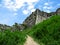 Stone ruined walls of Khust fortress are overgrown with grass - bottom view. The gloomy gray remnants of a medieval castle against