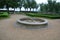 Stone sandstone circular fountain in the park. built of sandstone filled with water. lined with a light threshing gravel road with