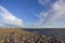 Stone sea promenade in the sandy desert against the white cable-stayed bridge and the modern city under a heavy blue sky