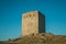 Stone square tower over rocky hill on sunset