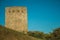 Stone square tower over rocky hill on sunset