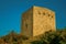 Stone square tower over rocky hill on sunset