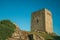 Stone square tower over rocky hill on sunset