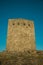 Stone square tower over rocky hill on sunset