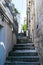 Stone stairs on narrow street among medieval walls in small town of Croatia. Stairs in the city. Old wall and metal fence with