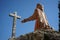 stone statue symbolizing a man kneeling before a crucifix representative of Catholicism