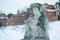 Stone statue in winter under the snow. City details.