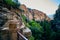 Stone steps in mountains with metal railing leading up mountain with view of large cliffs and forest