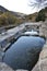 Stone thermal water pools and wooden benches next to the Cidacos river.