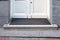 Stone threshold with foot mat at the entrance door made of white wood.