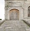 Stone tiled ramp leading to a wooden aged door over a stone wall