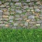 Stone wall background framed by lush green grass, natural harmony