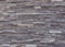 Stone wall cladding made of irregular dark gray stripes of natural rocks.