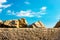 On a stone wall, in focus and out of focus are small stones against a blue sky that give the impression of a desert.