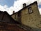 A stone wall of an old abandoned ruined house, windows, wooden ladder, chimney and house roof.