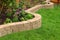 Stone wall with perfect grass landscaping in garden with artificial grass