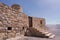 Stone wall of a small medieval arabian fort with wooden door and stone stairs in Bukha, Oman.