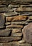 Stone wall texture with unevenly stacked rocks and cement ground