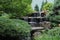 A stone waterfall cascading into a pond in a landscaped Japanese garden in Wisconsin