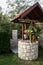 Stone well with a wooden roof and a bucket of water in beautifully garden