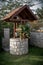 Stone well with a wooden roof and a bucket of water in modern garden