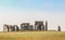 Stonehenge on a clear summer day viewed across the field with a bird sitting on top of one of the rocks