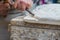 Stonemason works a white stone with hammer and chisel. Hands with tools and white stone block