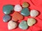 Stones in the shape of heart lie on a red background. Heart made of natural quartz stone, rhodochrosite, jade, aventurine and