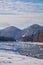 Stones with snow caps in the water of Altai Biya river under heavy snow in winter season with forest on background