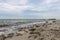 Stony Baltic Sea coast with pebbles, waves and clouds blue sky