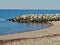 Stony bay with stone built wall with large blocks of rock and sea in background