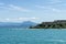 Stony Beach of Sirmione town on Garda Lake with view of Grottoes of Catullus.