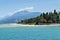 Stony Beach of Sirmione town on Garda Lake with view of Grottoes of Catullus.