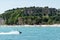 Stony Beach of Sirmione town on Garda Lake with view of Grottoes of Catullus.