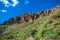 Stony cliffs on background blue sky with clouds, green foot