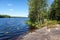 Stony lake shore with green trees, the Saimaa Canal is near the Vyborg town, Russia. Horizontal image