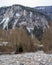 A stony little low-lying river flows against a mountain backdrop from its source in Switzerland